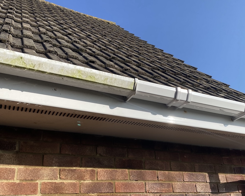 Dirty soffits, fascias and gutters being cleaned on a house.