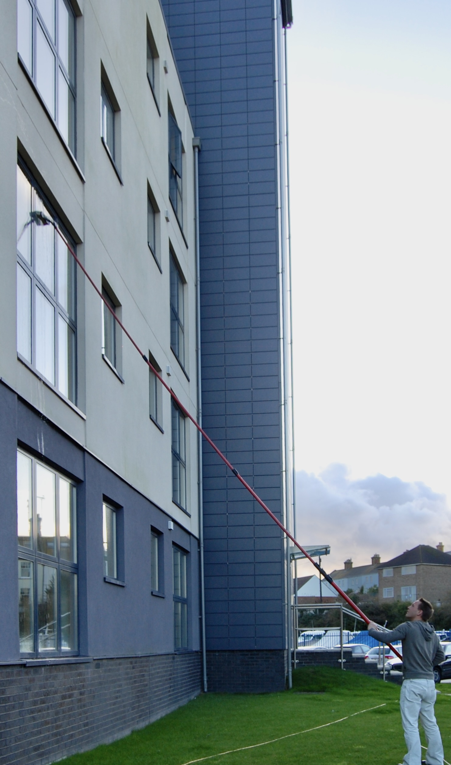 Cleaning windows on a block of flats using a water fed pole.